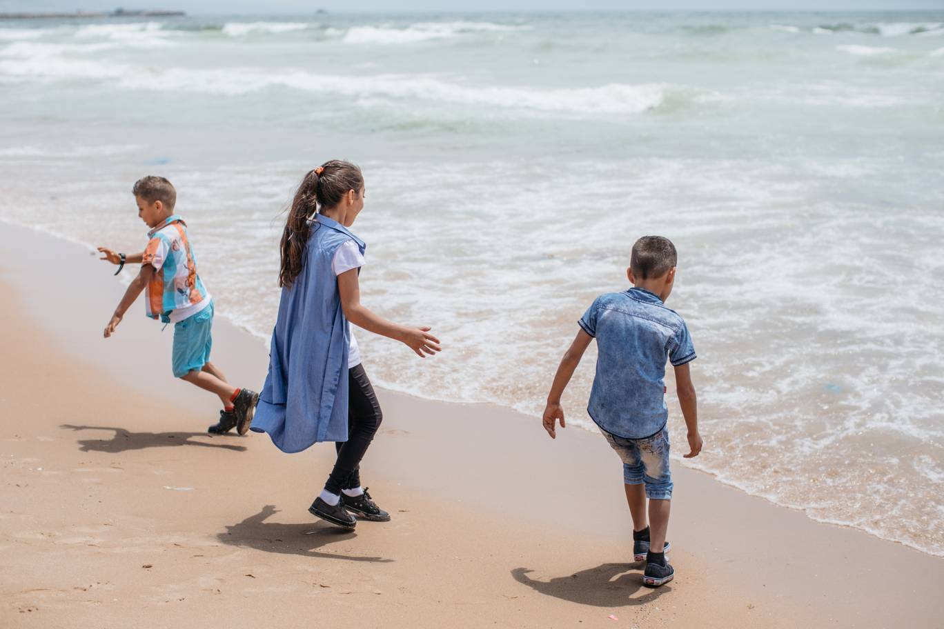 Sara, Ali and Deeb chase the white water on Lebanon’s coastline. As the waves break on the sand, so too do the barriers between siblings. They laugh together and have forgotten about their struggle for now - Photo by Paddy Dowling