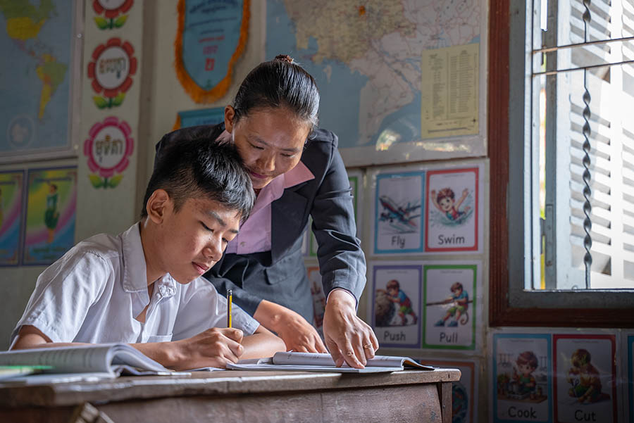 Heng Lyhong with his teacher works on his school exercises.