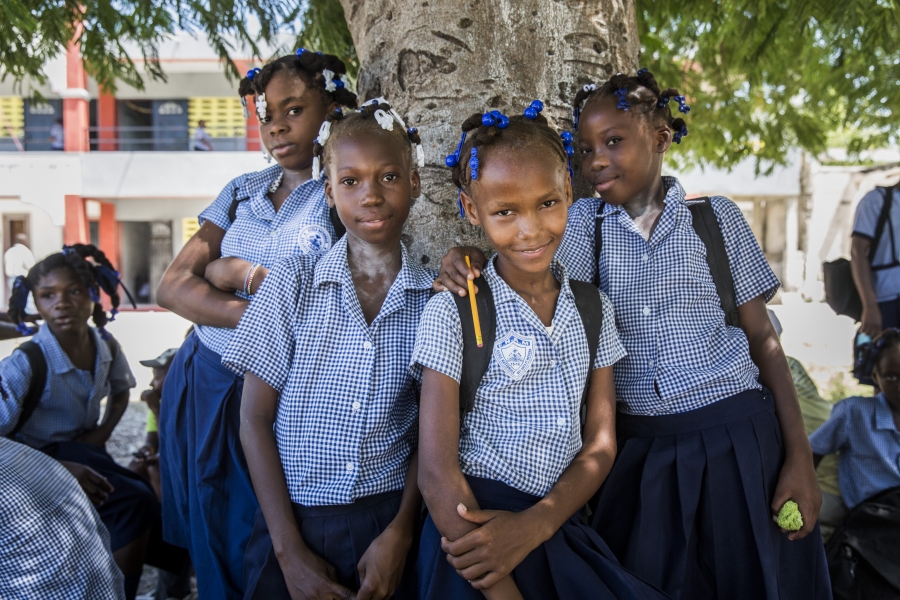 Children in uniforms standing in front of a tree.