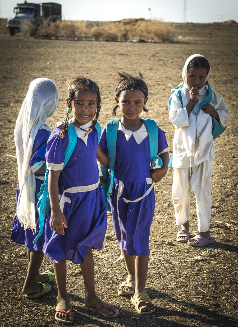 Girls stand in uniforms in a rural area.